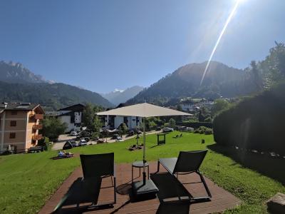 Vue montagne avec chaises longues et parasol dans jardin ensoleillé.