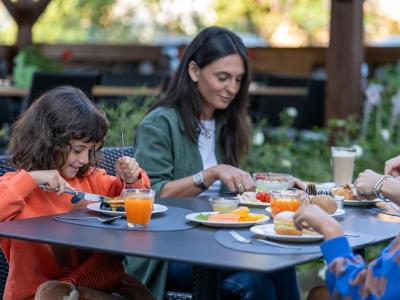 Famiglia felice fa colazione all'aperto, tra sorrisi e piatti colorati.