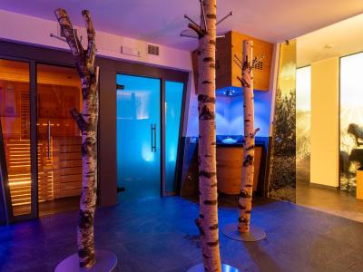Ambiente rilassante con sauna, luci soffuse blu e tronchi decorativi.