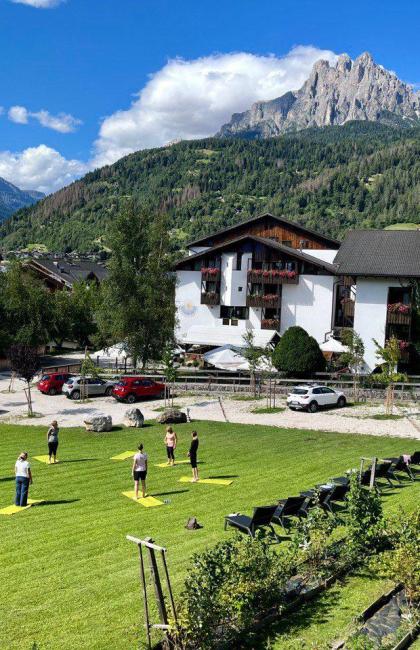 Yoga all'aperto tra montagne e cielo azzurro, serenità e natura.
