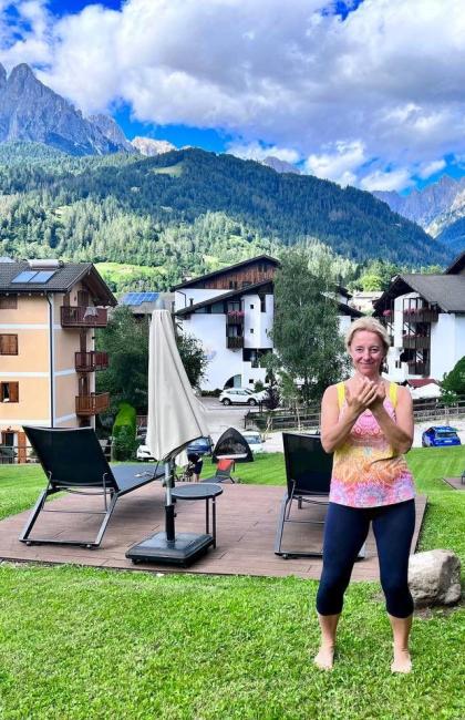 Donna felice in montagna, paesaggio alpino, cielo blu e case pittoresche.