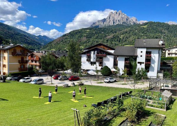 Yoga all'aperto tra montagne e cielo azzurro, serenità e natura.