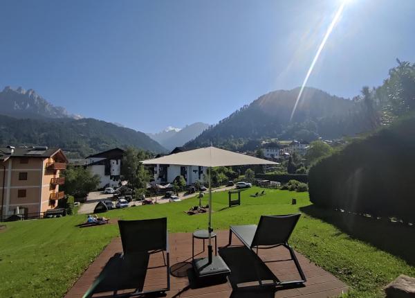 Vue montagne avec chaises longues et parasol dans jardin ensoleillé.