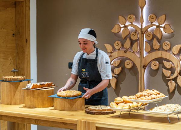 Konditorin mit Desserts auf dekoriertem Holztisch.