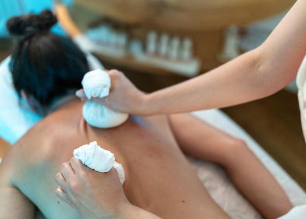 Massaggio rilassante con tamponi caldi su schiena nuda, atmosfera di benessere.