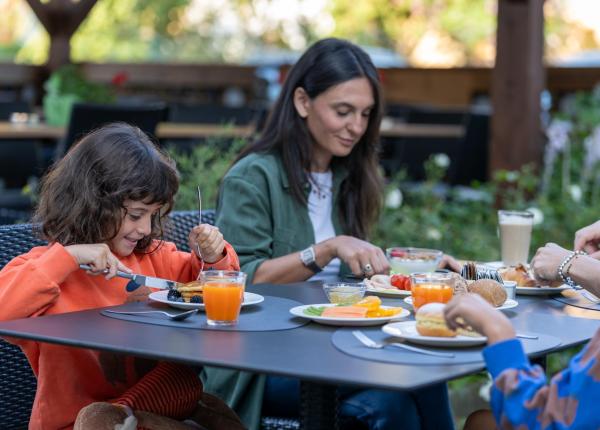 Famiglia felice fa colazione all'aperto, tra sorrisi e piatti colorati.