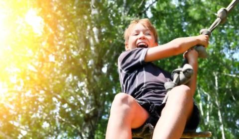 Happy child on a swing among trees.