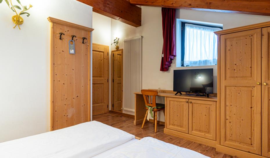 Camera accogliente con mobili in legno, TV e finestra.