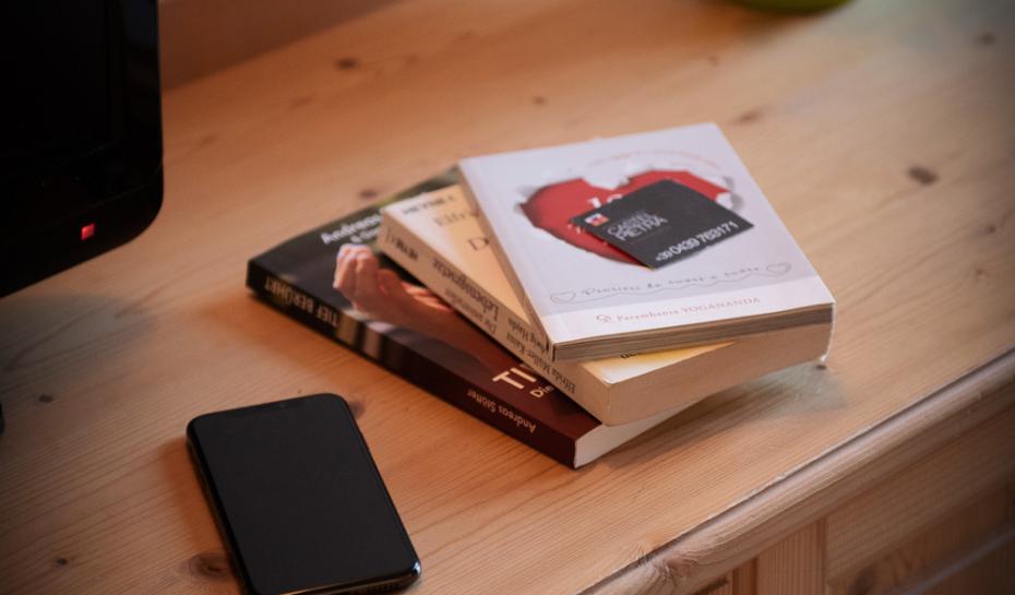 Scrivania con libri, telefono e pianta in vaso verde.