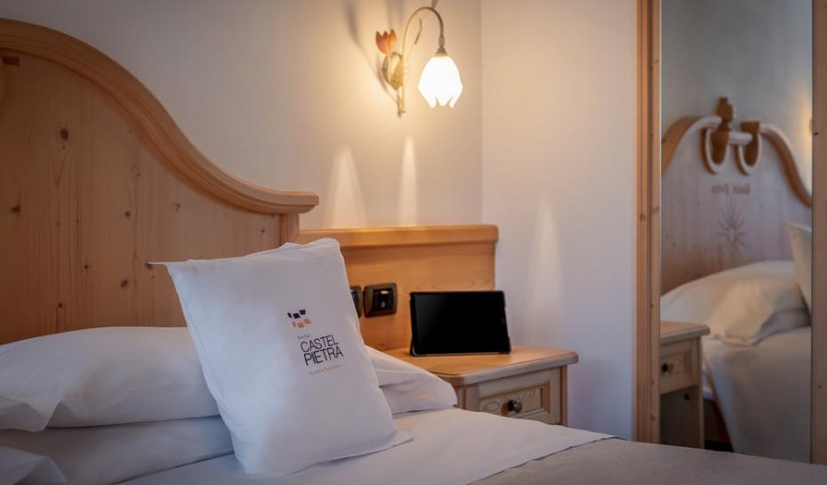Camera d'albergo accogliente con cuscino personalizzato e tablet.